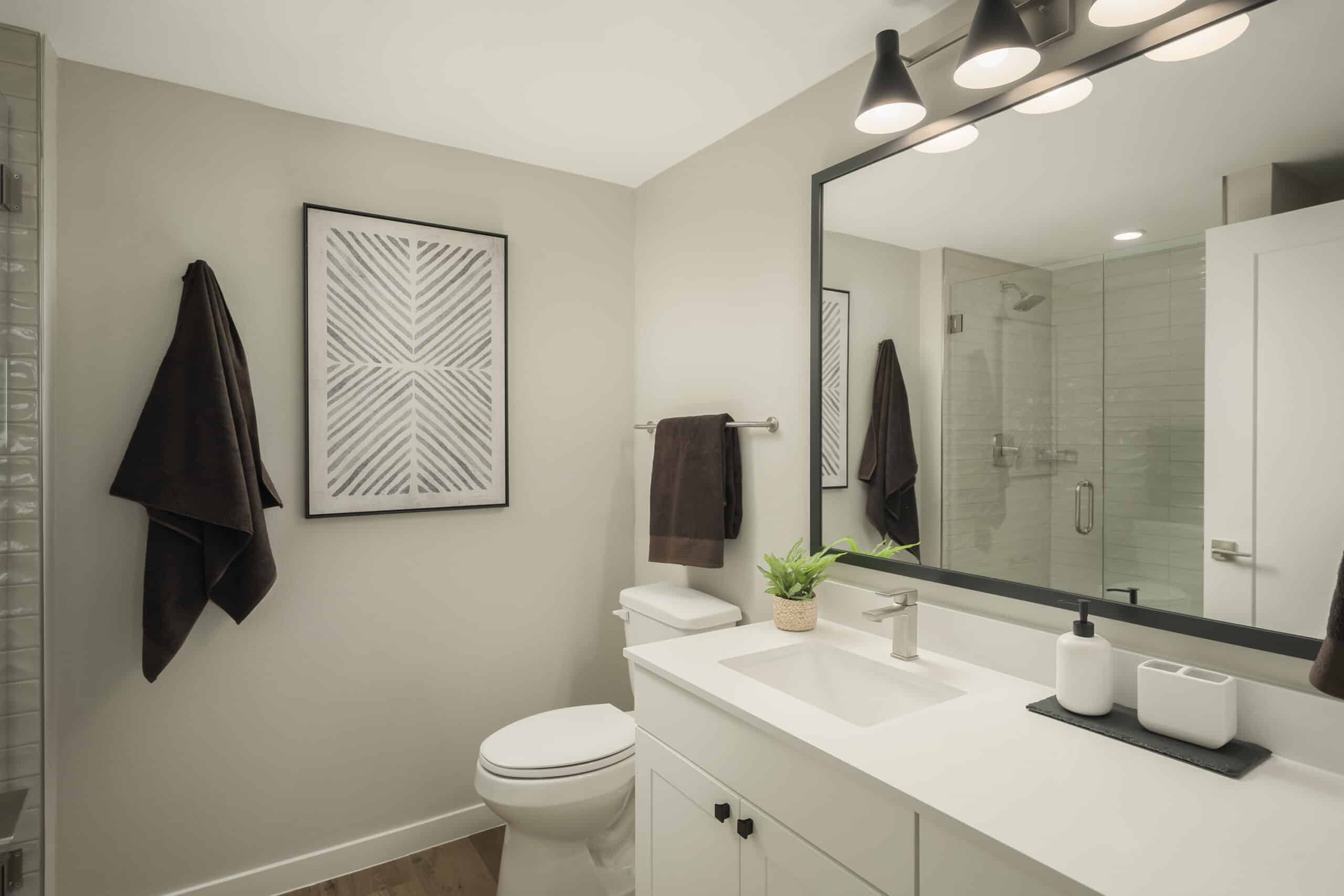 A bathroom with double vanity, large mirror, and neutral color scheme.