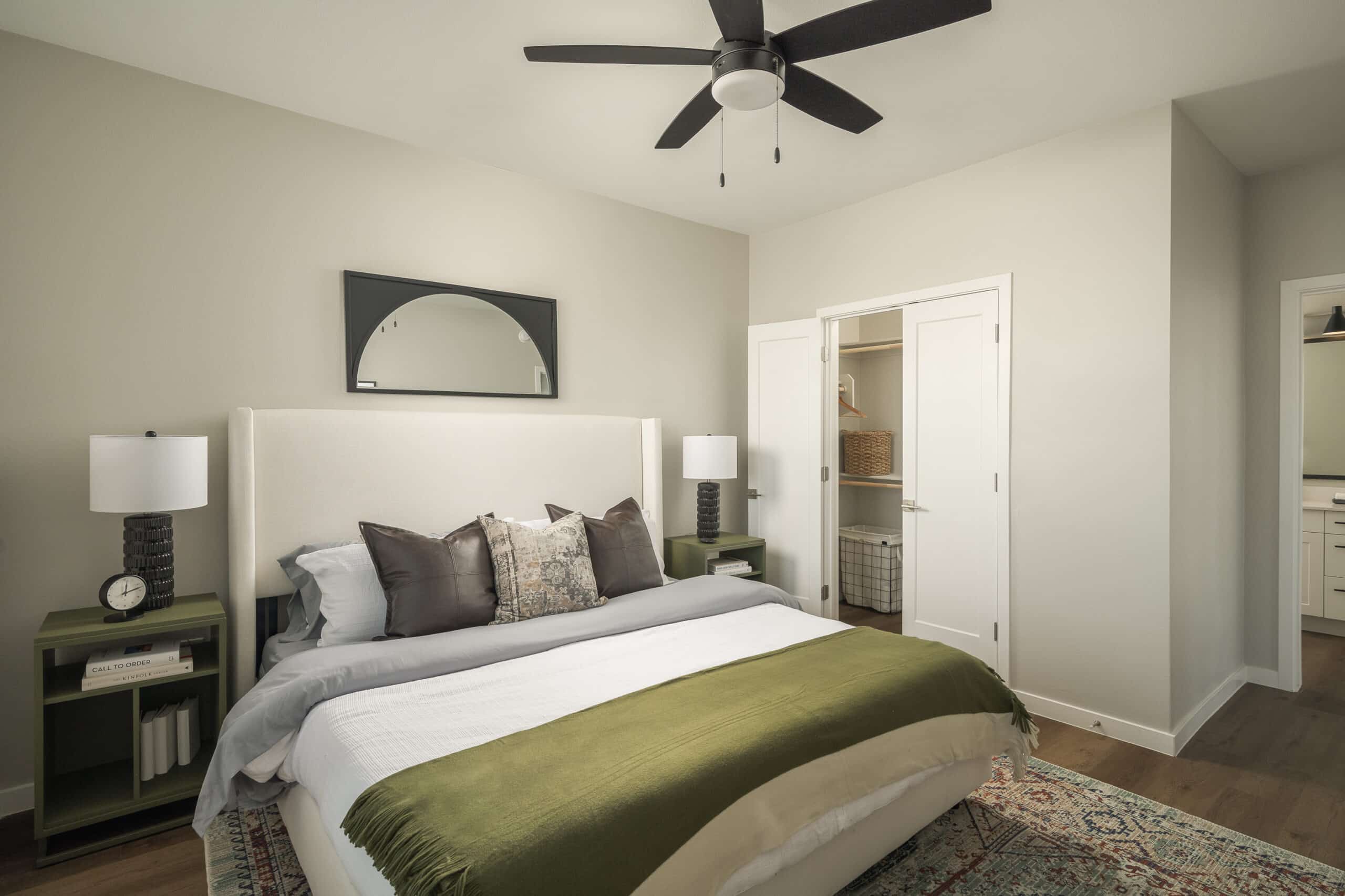 Bedroom with a bed, side tables with lamps, a ceiling fan, and an open closet.