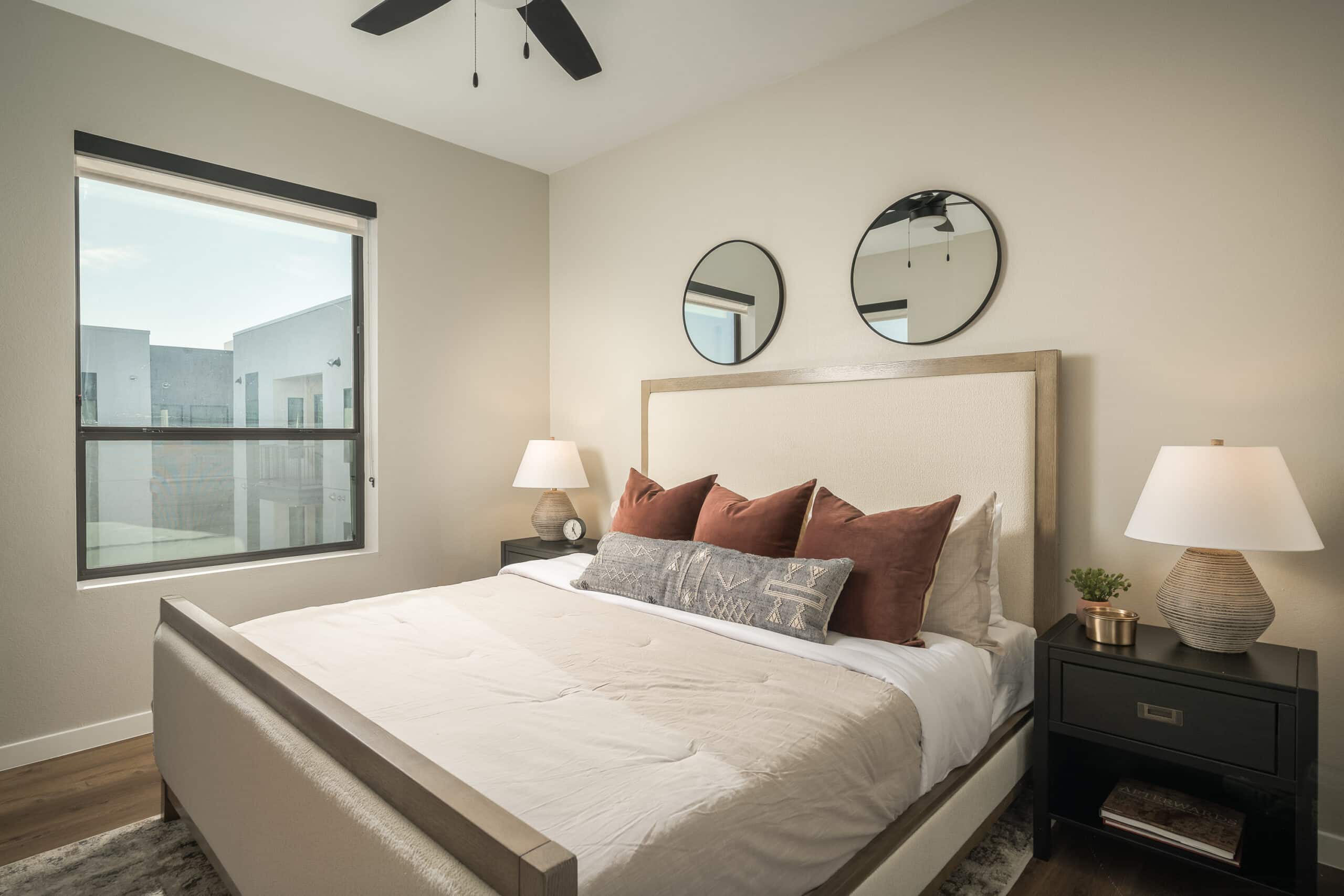 A bed with a round mirror above it.