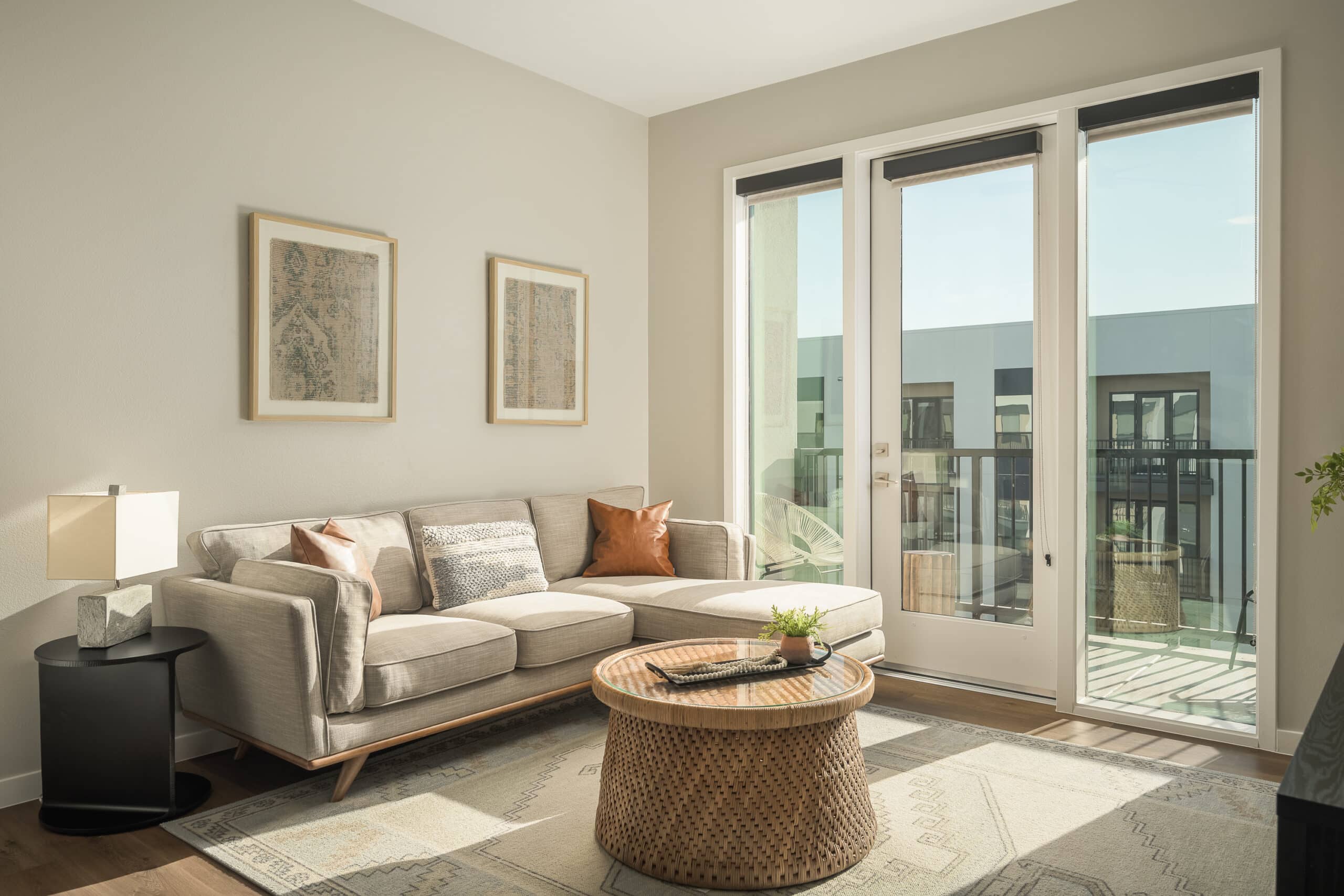 A well-lit, modern living room with a neutral color palette, featuring a comfortable sofa and a round coffee table.