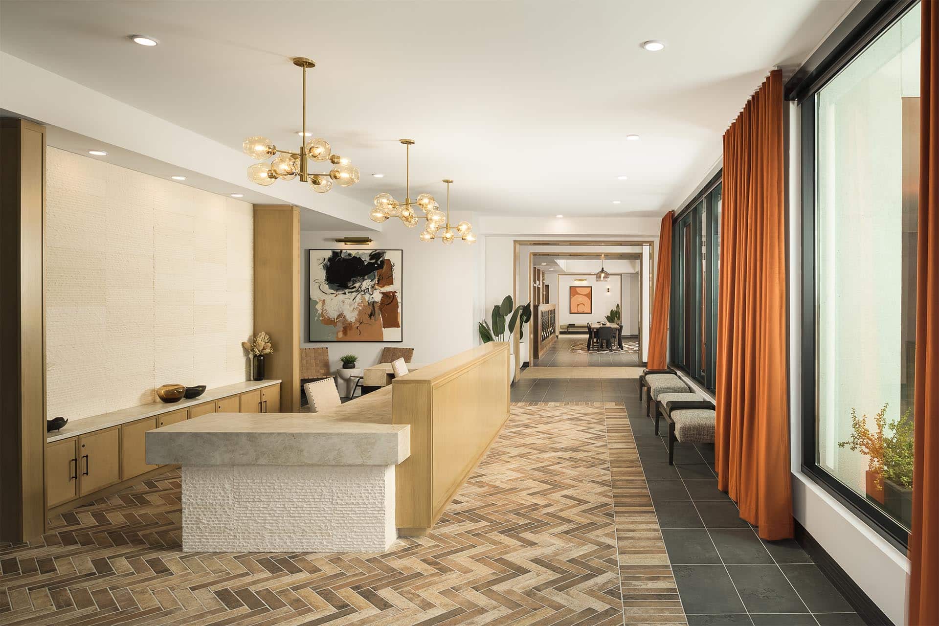 Modern reception area with a stylish waiting bench, reception desk, decorative lighting, and a view into adjacent rooms.